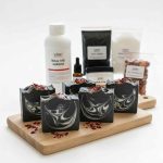 Aktif karbonlu çay ağacı yağlı el yapımı siyah sabunlar ve arka planda sabun yapım malzemeleri