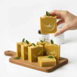 El yapımı sarı soğuk süreç sabunları, ahşap tahtada sergilenmiş, dekoratif yapraklı doğal sabunlar